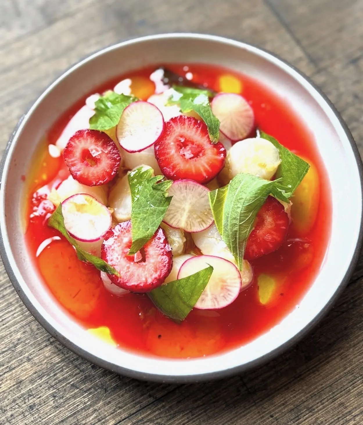 Sliced strawberries, radish, baby turnips and shiso in chilled tomato consommé — Montecito private chef summer course